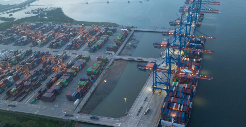 Port with cargo ship carrying reefer containers used in pharmaceutical temperature controlled sea freight.