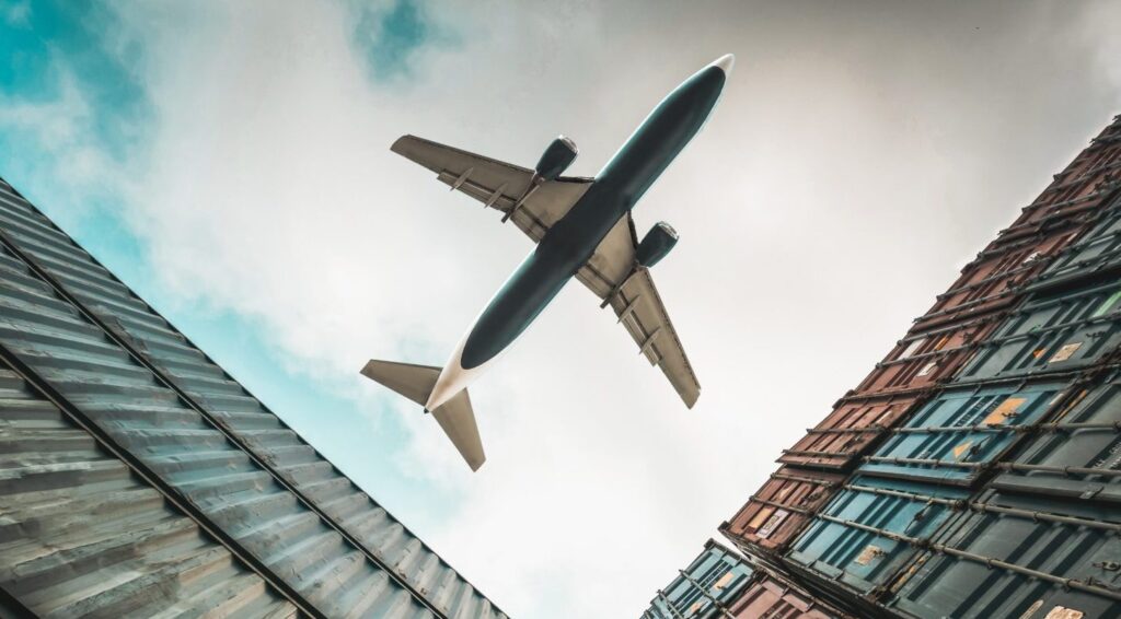 Air freight in pharma logistics: cargo plane flying over refrigerated containers transporting temperature-sensitive goods